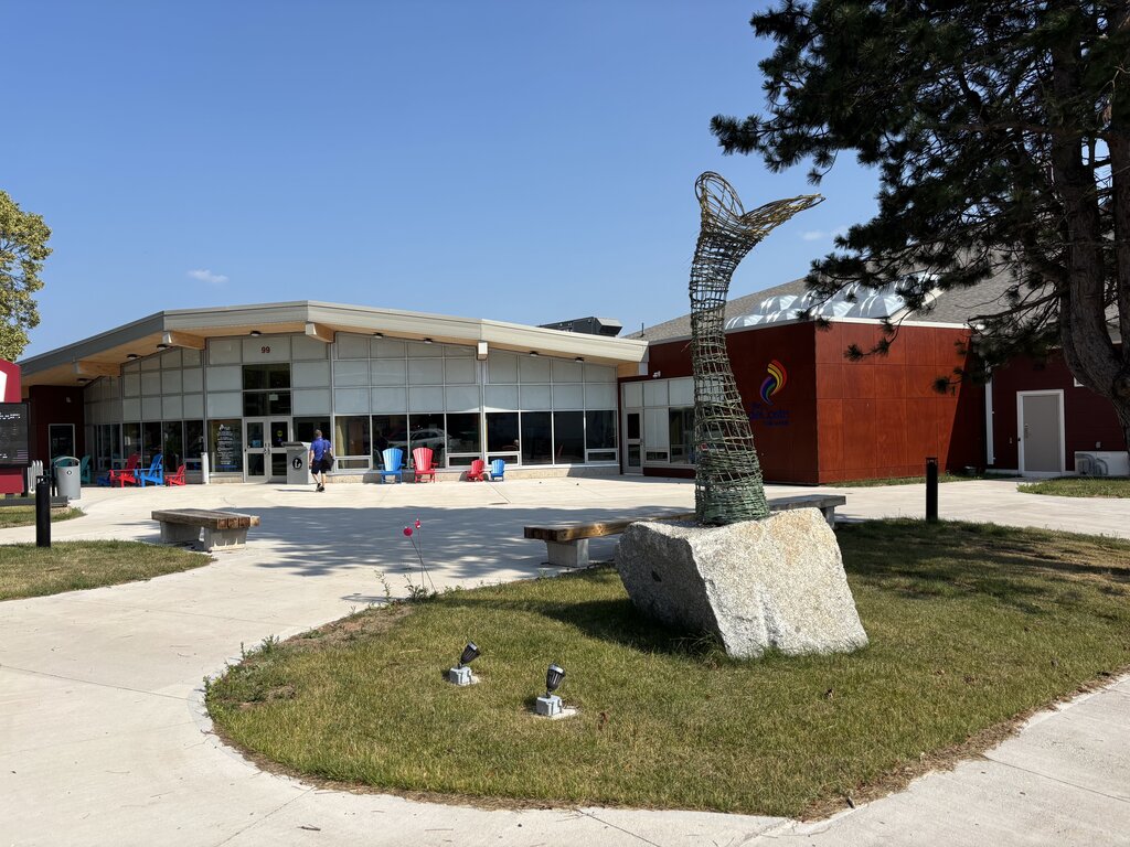 The deCoste Performing Arts Centre in Pictou, Nova Scotia features a modern glass entrance and a metal whale tail sculpture out front.