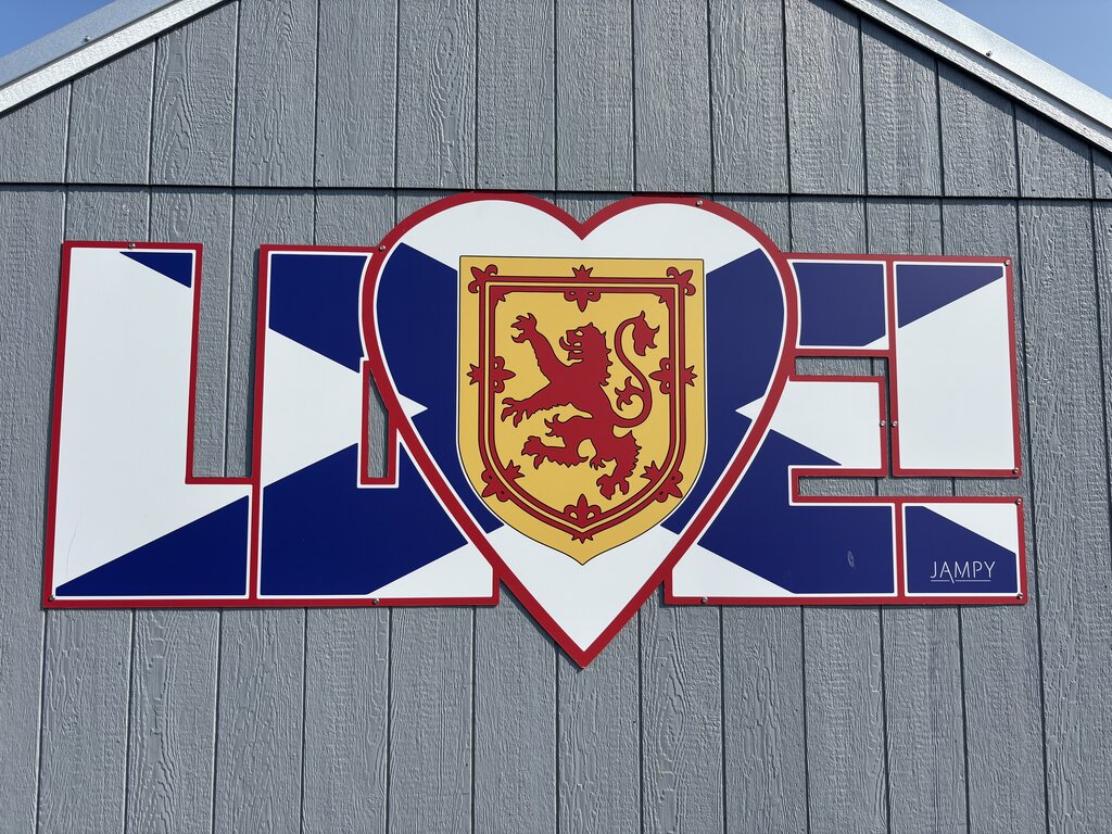 A mural on a gray wall spells out “LOVE” using the Nova Scotia flag as the background and a heart with the province's crest as the “O”.