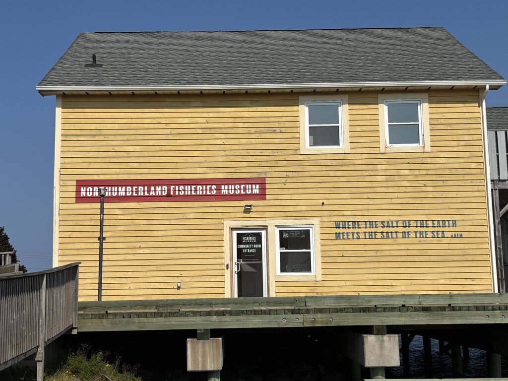 The Northumberland Fisheries Museum in Pictou features a yellow wooden exterior with the quote “Where the salt of the earth meets the salt of the sea” painted on the side.